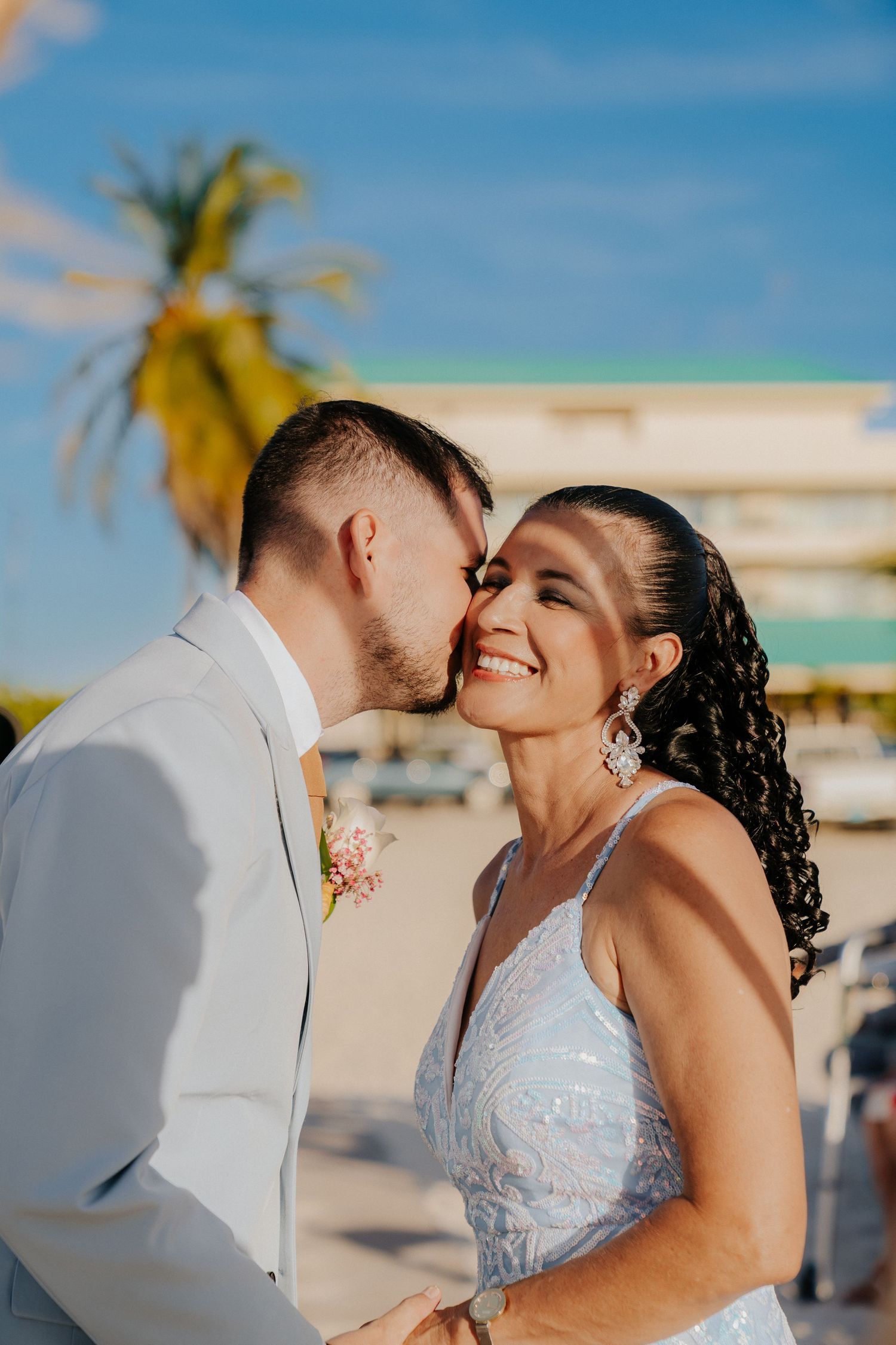 A tender moment shared during a beach wedding with palm trees in the background.