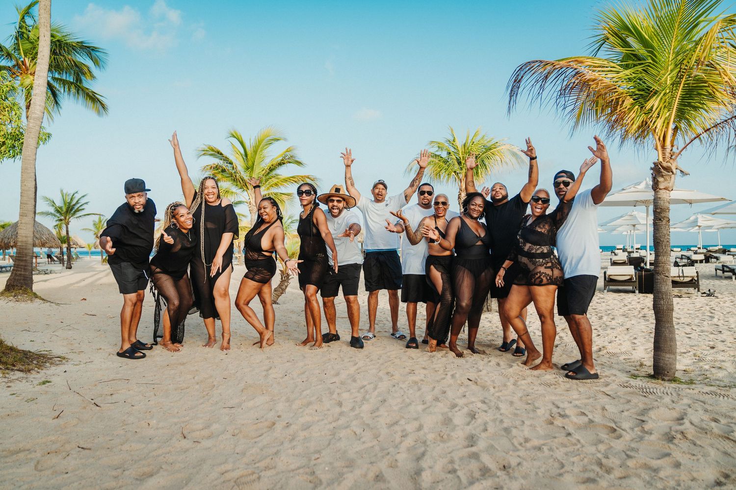 Group photo of people posing together on a tropical beach with palm trees.
