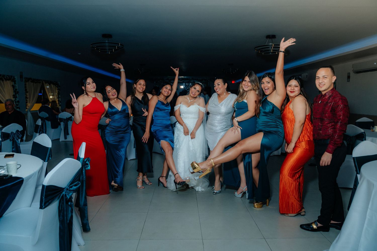 Wedding guests dancing energetically at a reception with blue lighting and festive atmosphere.