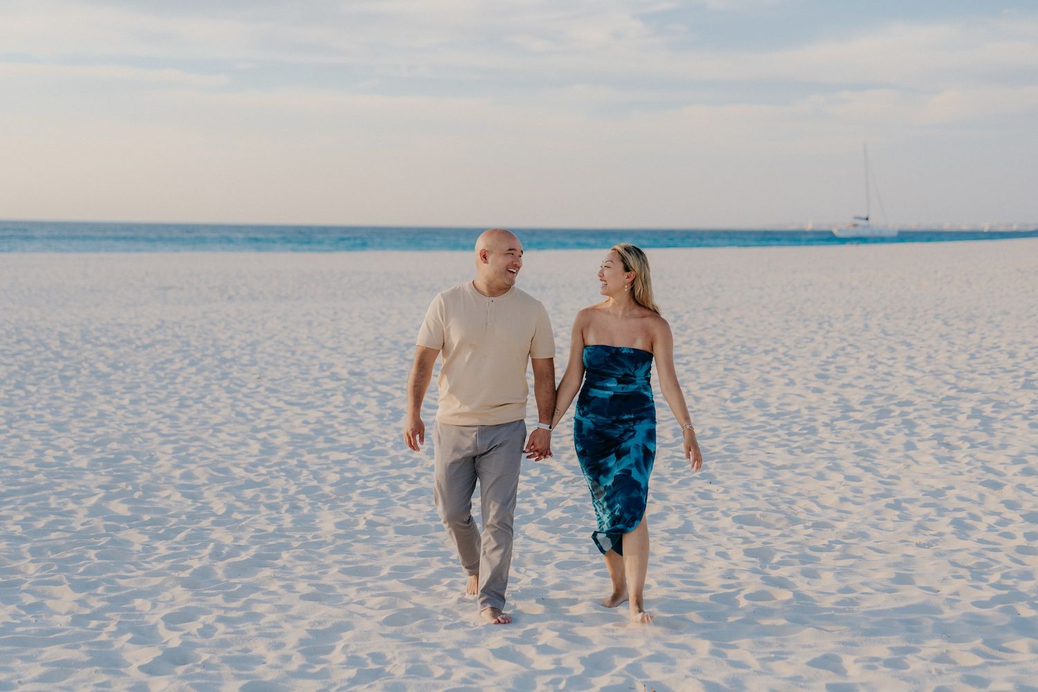 People walking together on a pristine white sand beach with calm waters in the background.