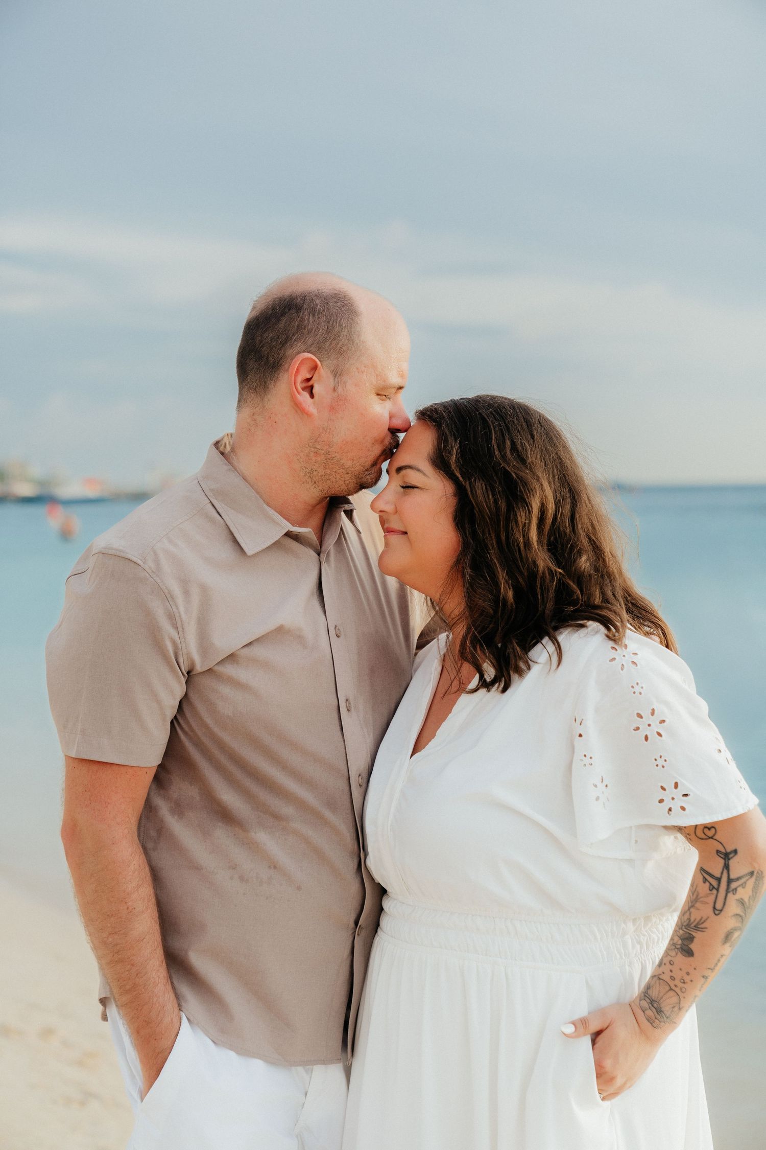 A romantic beach photo series with a couple in light summer attire against the ocean.