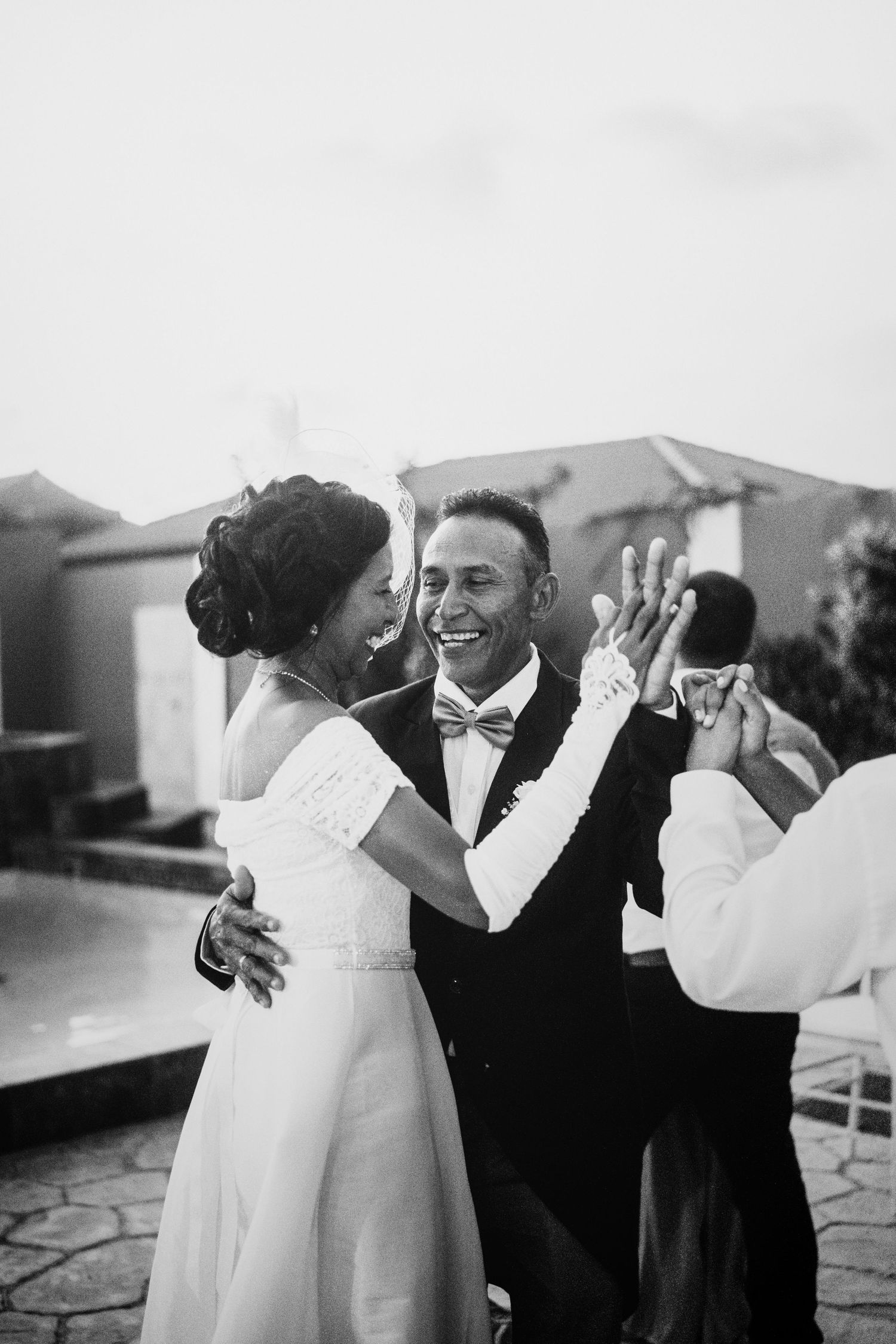 Couple dancing together at outdoor wedding celebration in black and white.