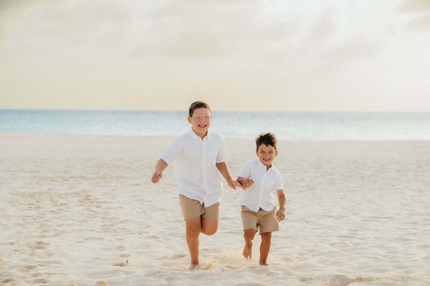 Two people run and play together on a pristine white sand beach.
