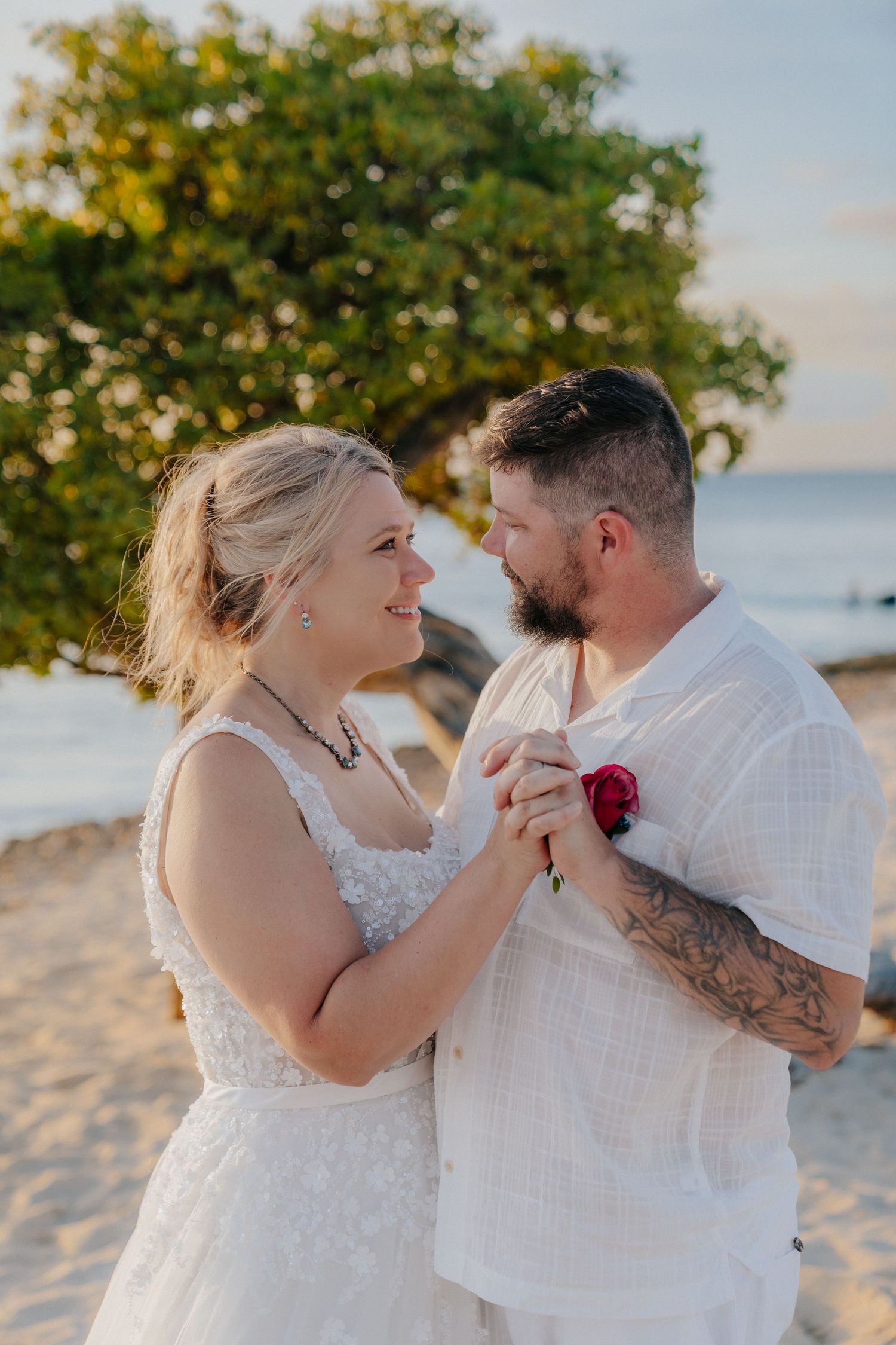 A romantic beach wedding photoshoot with a couple in white against a scenic coastal backdrop.