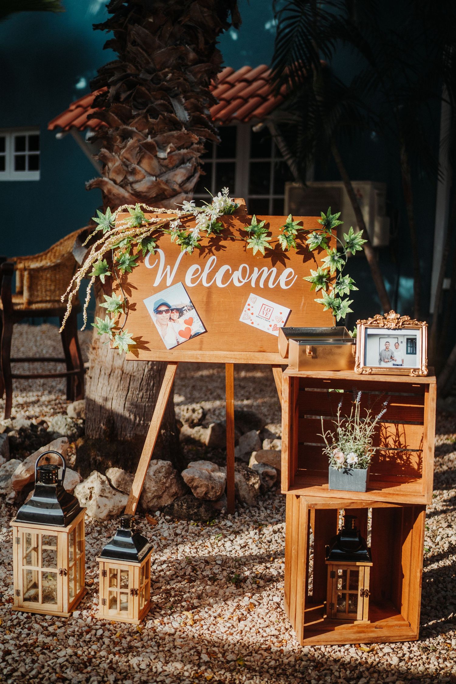 Rustic wedding welcome display with wooden crates, lanterns and floral decorations.