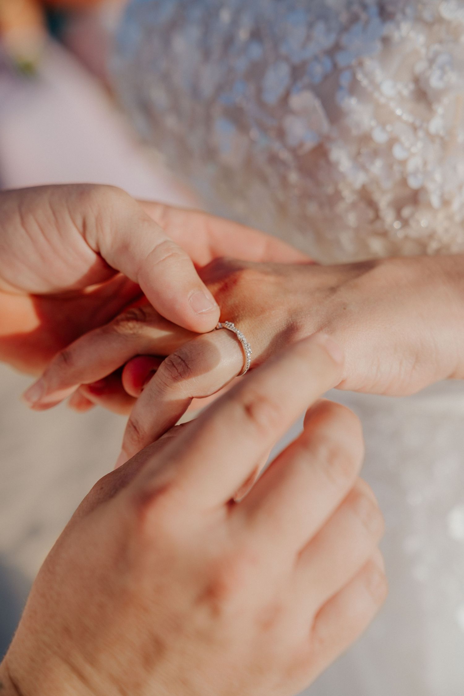 Close-up shot of hands exchanging wedding rings during ceremony.