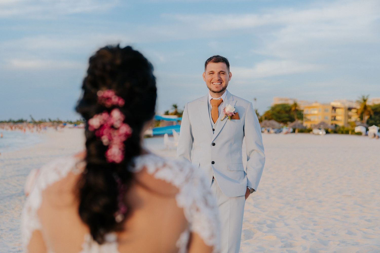 A romantic beach wedding ceremony at sunset with a couple embracing on white sand.