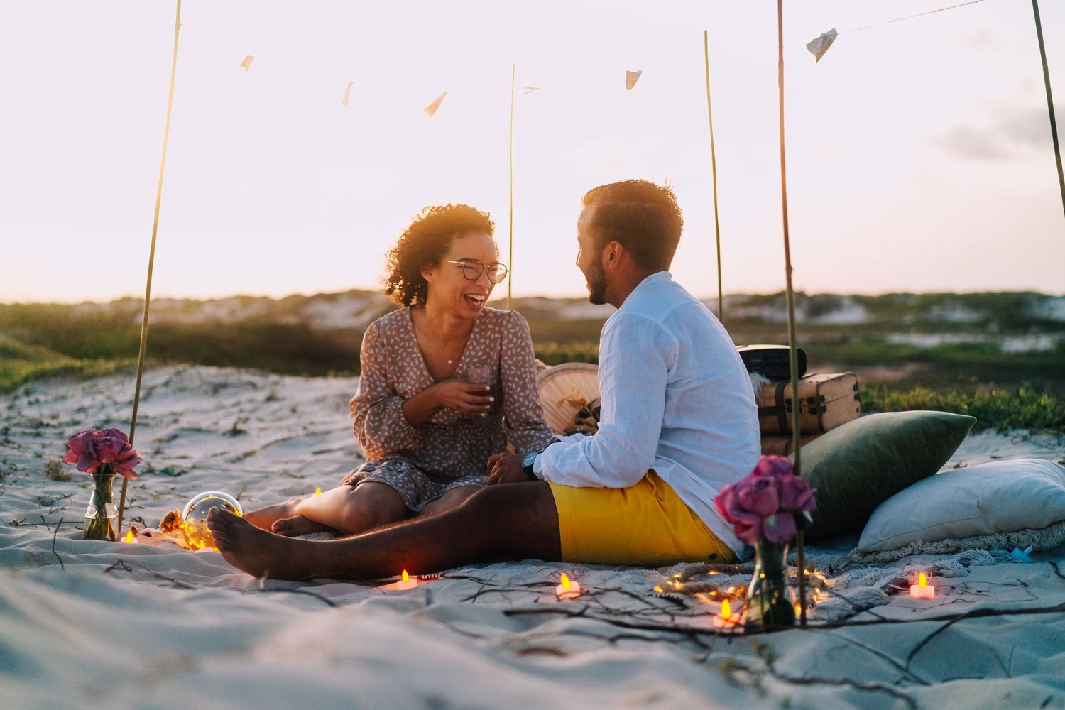 Couple having a romantic picnic on the beach at sunset.