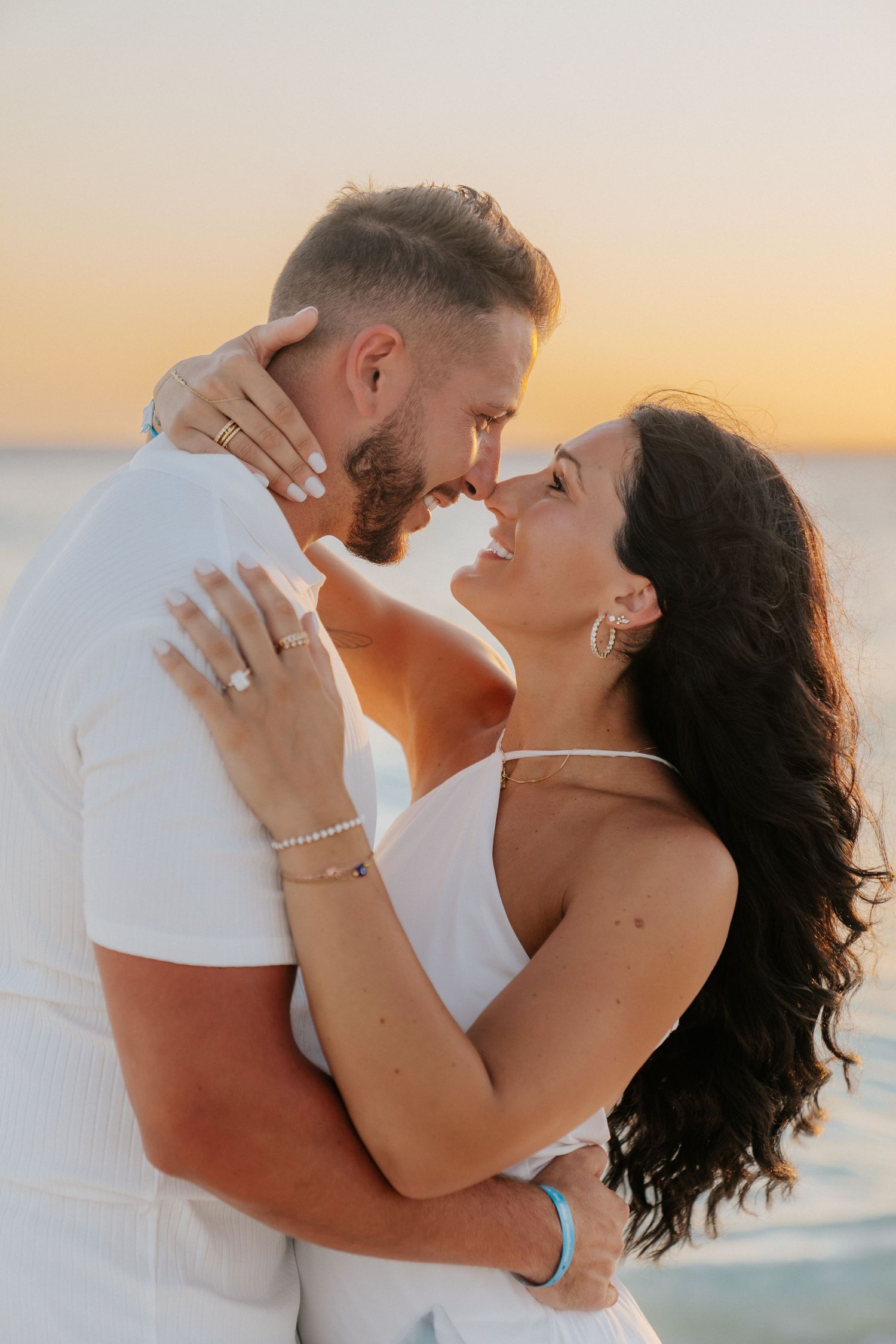 A couple shares an intimate embrace on the beach at sunset.