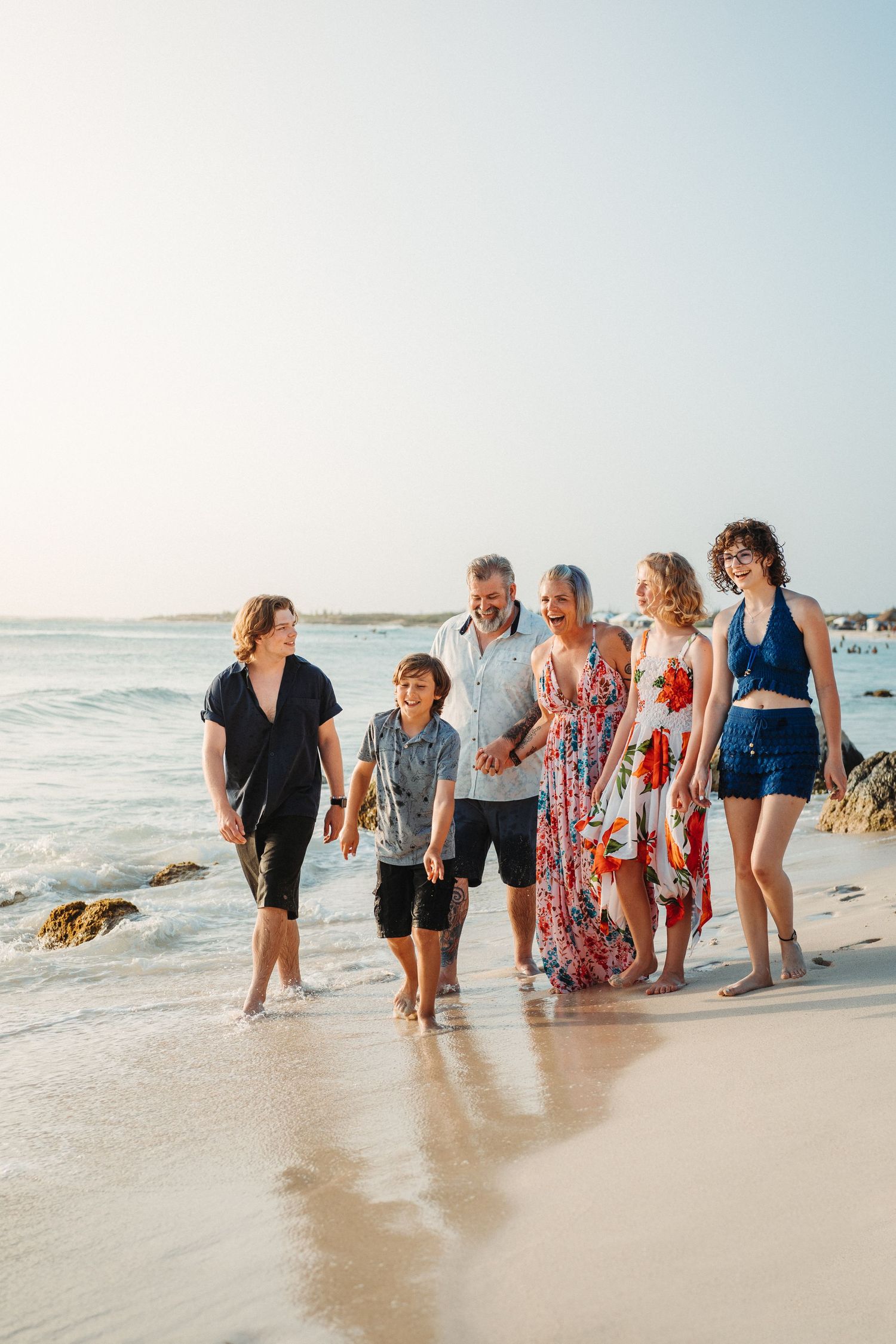 Joyful group walking along the shoreline at the beach during sunset.