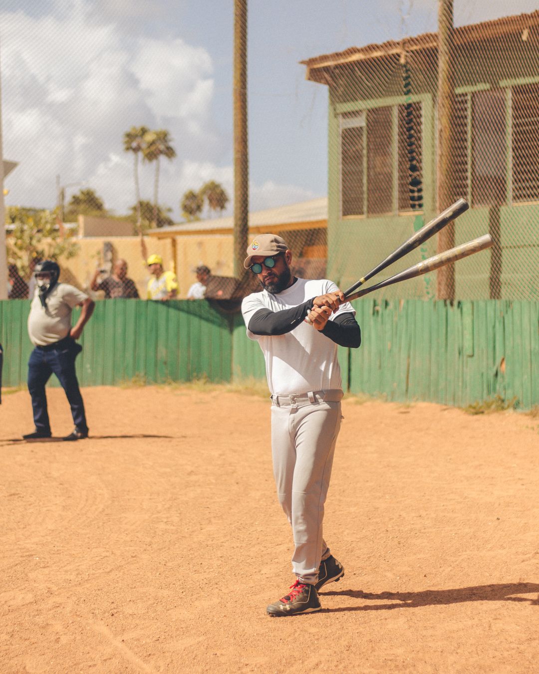 Baseball players practicing batting stances on a sandy field.