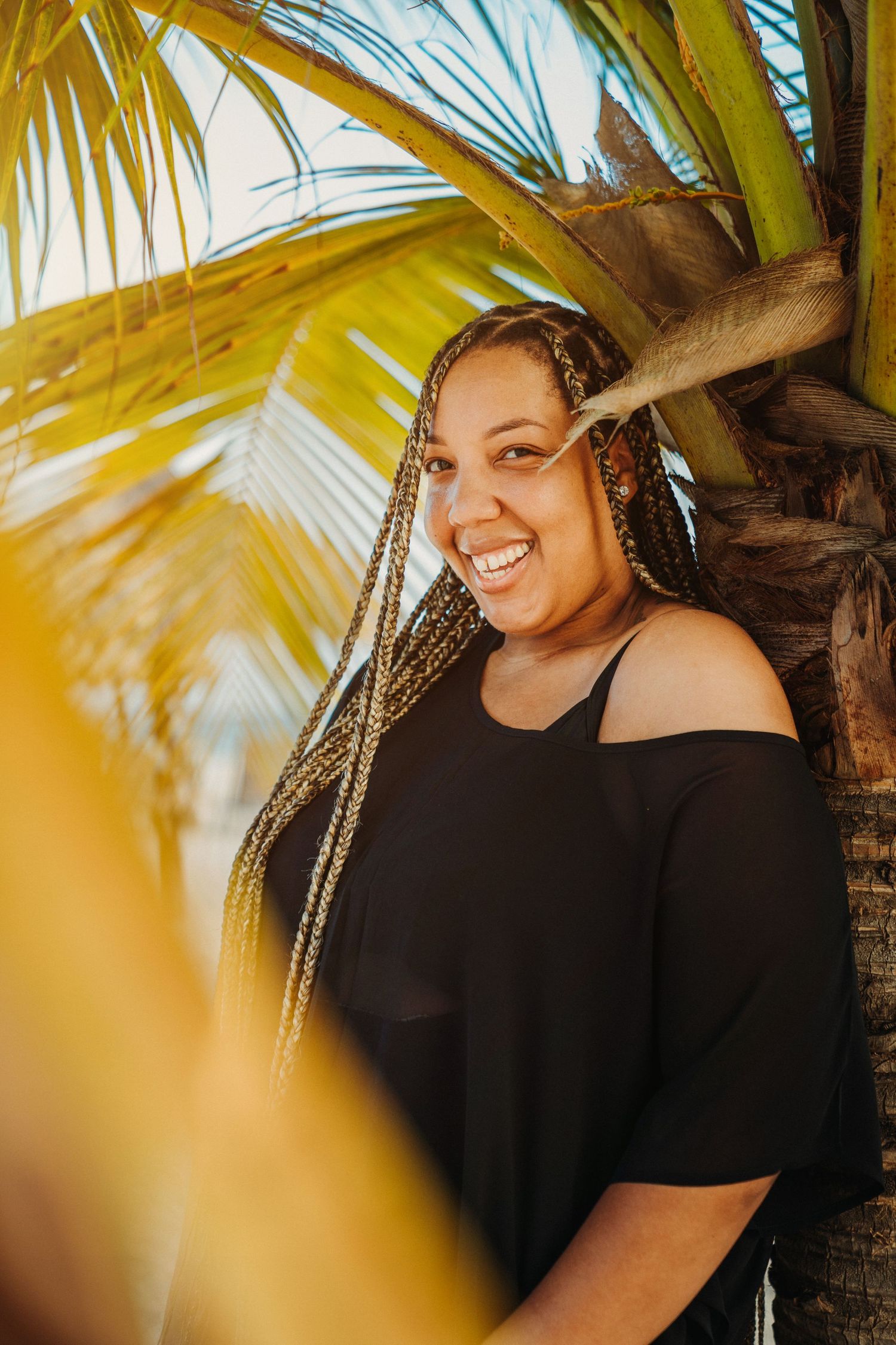 Portrait against palm trees with warm golden sunlight filtering through the leaves.