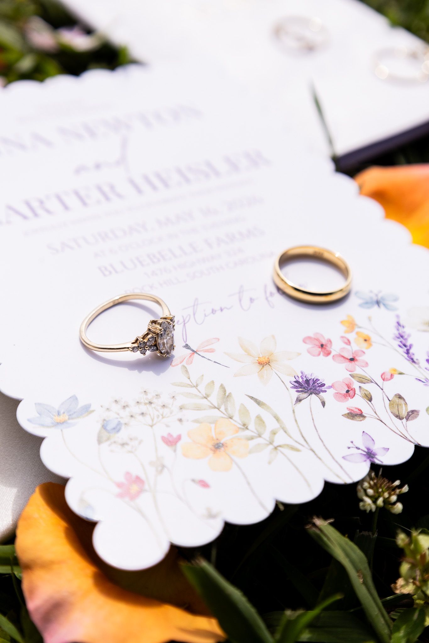 Wedding rings rest on floral wildflower invitation for Newton and Hessler at Bluebelle Farms.