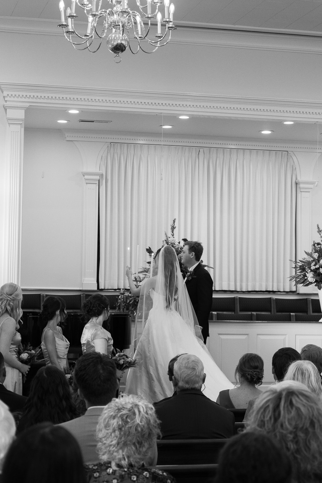 Black and white photo of a bride and groom kissing at the altar during a church wedding ceremony with guests seated.