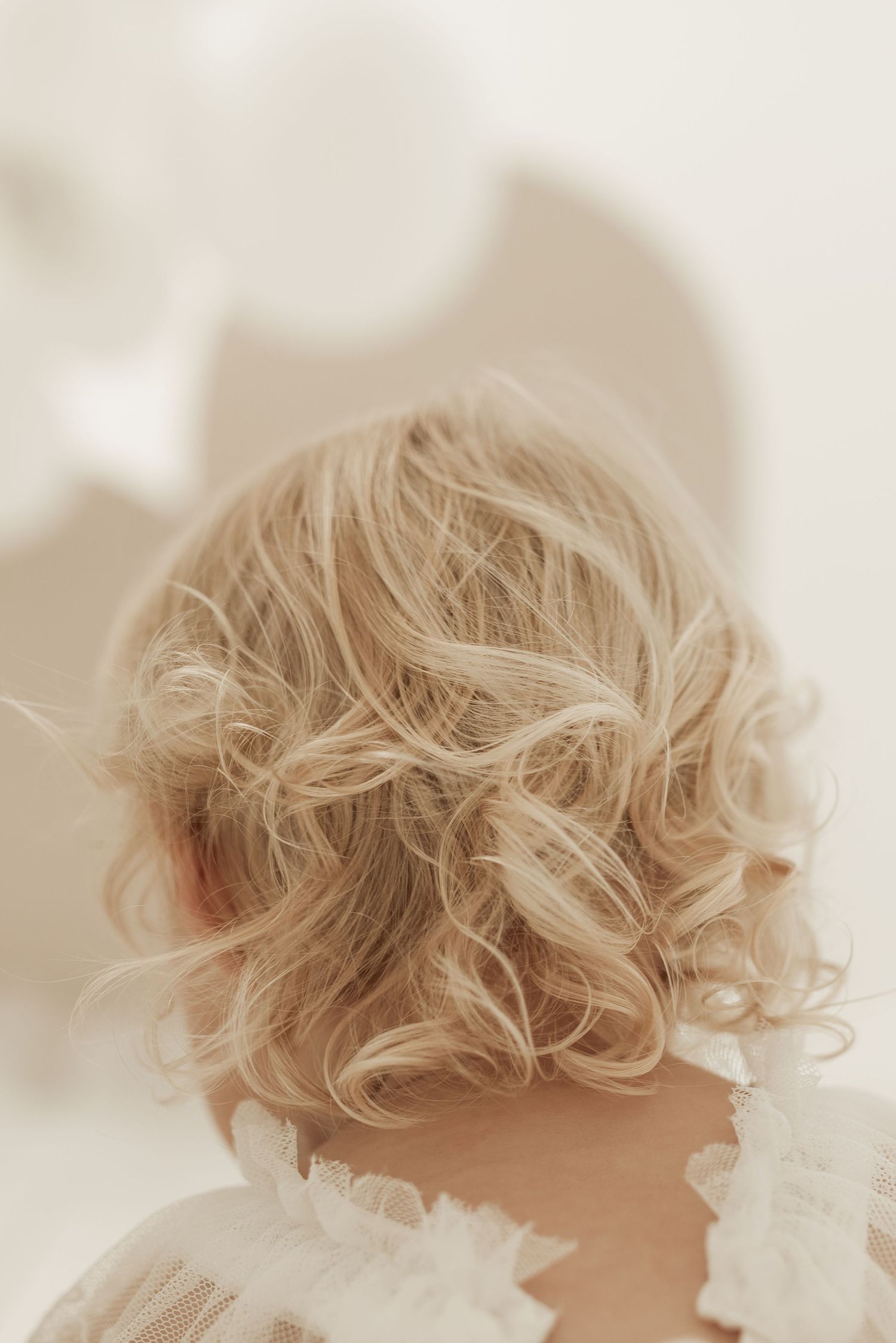 Close-up view of blonde curly hair against a soft white background.