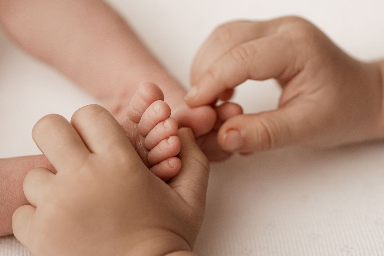 A close-up series of baby hands grasping and holding adult fingers against a soft white background.