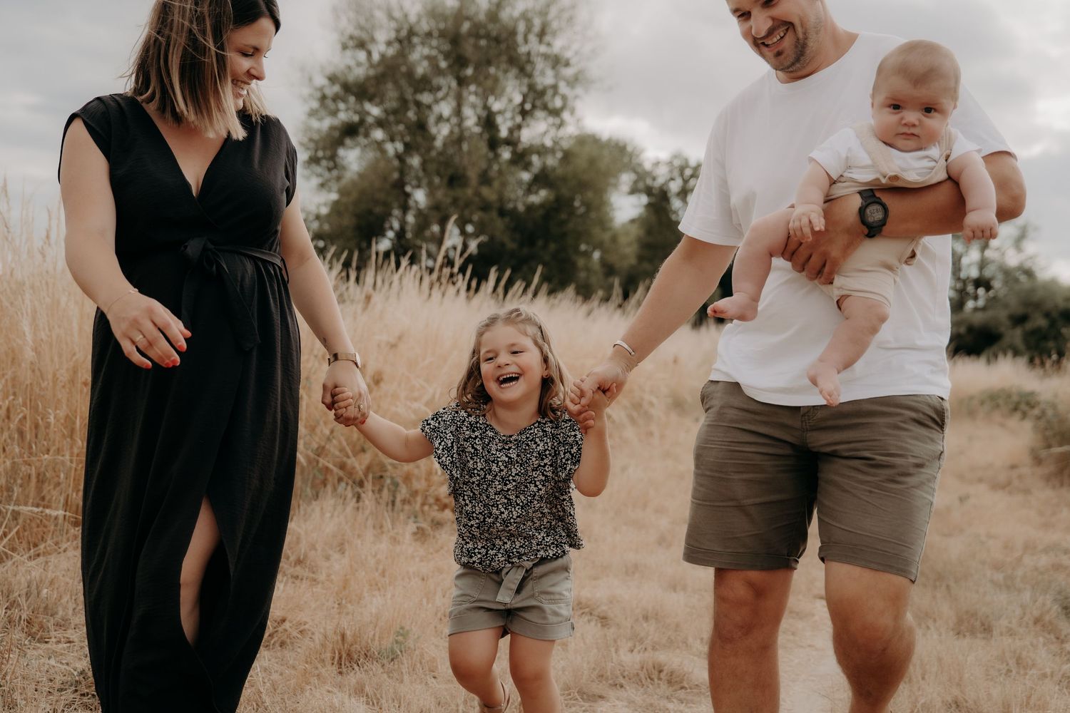 Family enjoying playful moment together in golden summer field.