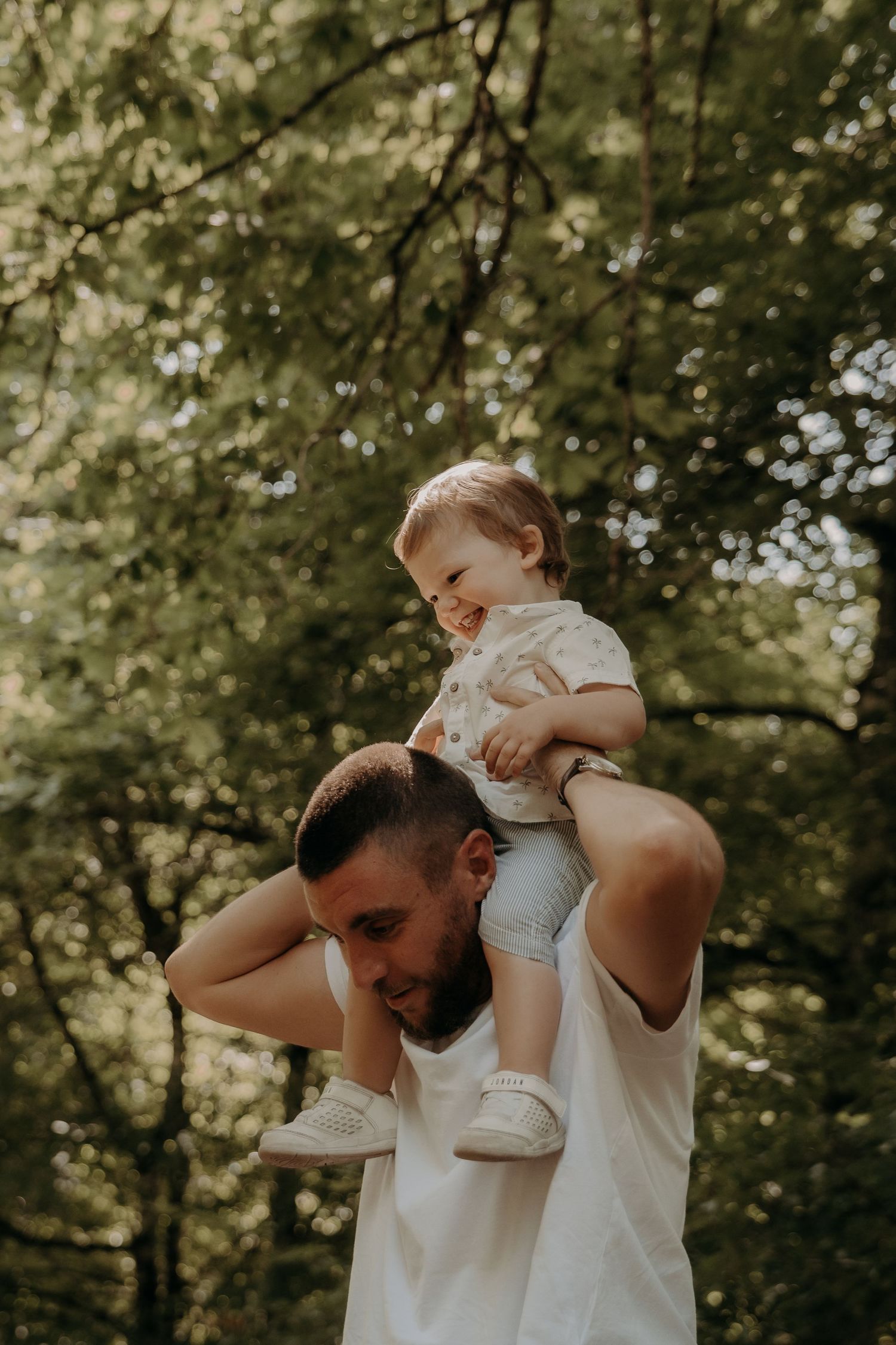 Joyful moment captured between parent and child in sunlit forest setting.