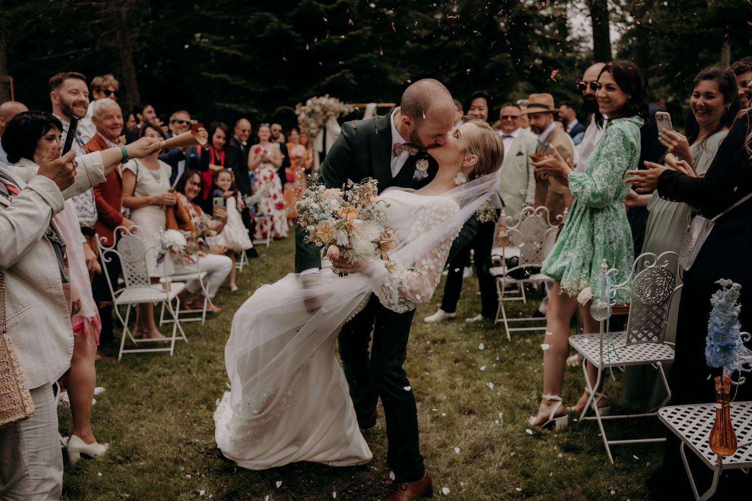 Wedding celebration scene with couple dancing surrounded by guests in outdoor garden setting.