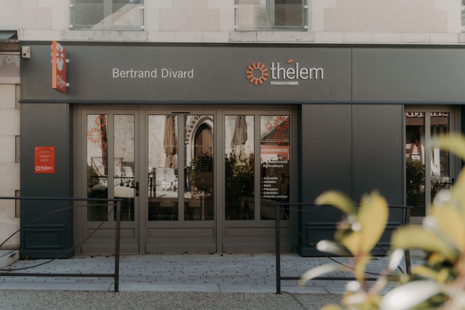Modern gray office building exterior with Thelem company signage and glass windows.