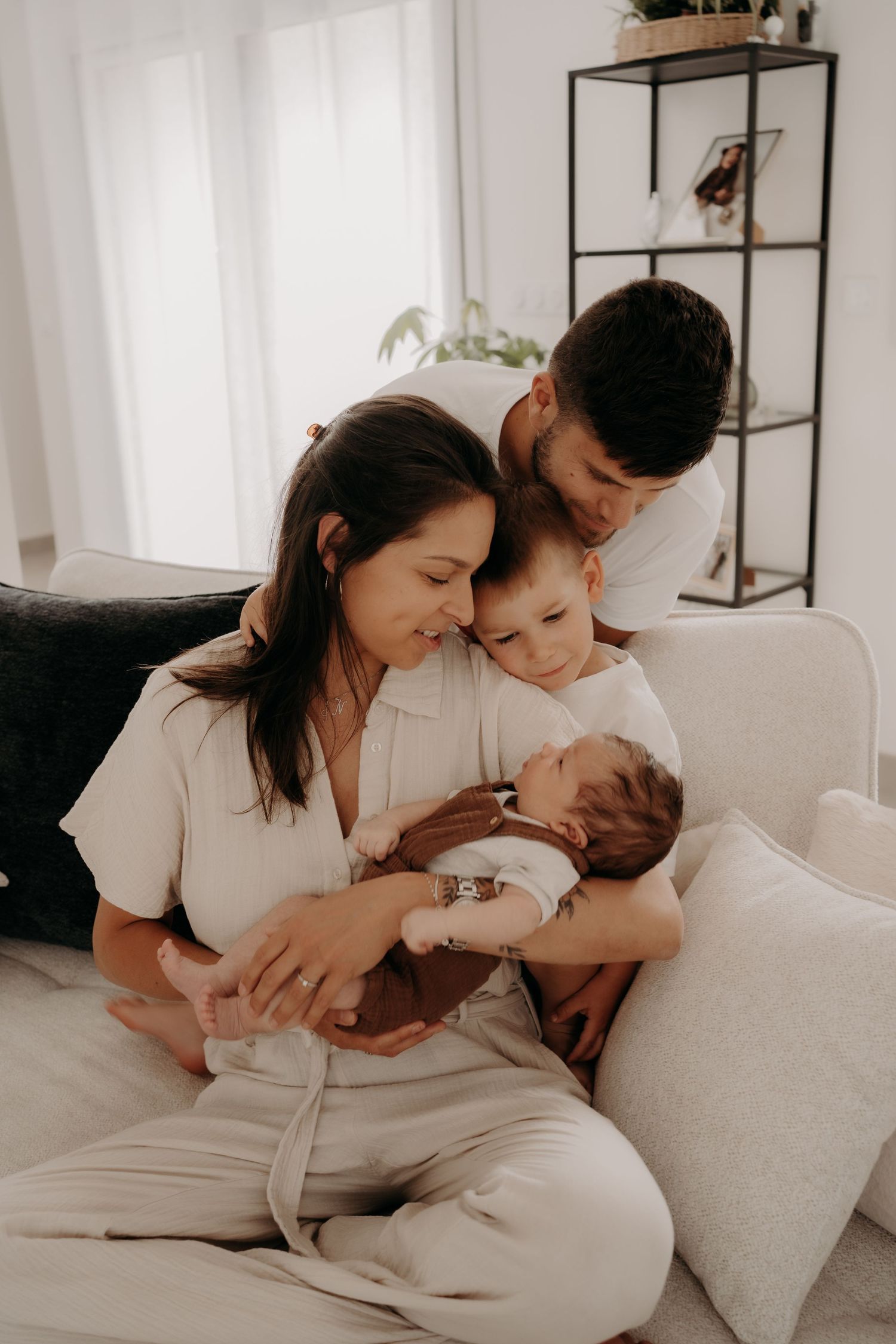 Intimate family lifestyle session on white couch in bright modern interior setting.