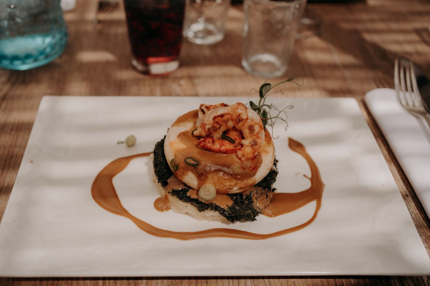 Plated gourmet dishes served on white tablecloths in an upscale restaurant setting.