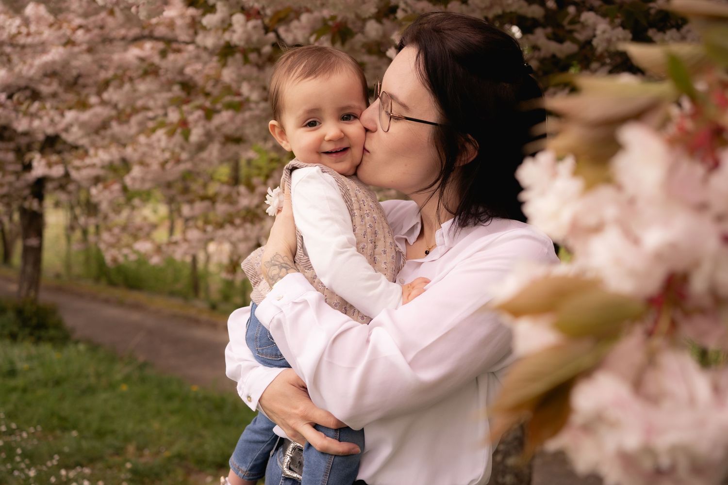 Tender moment between parent and child among blooming cherry blossoms.