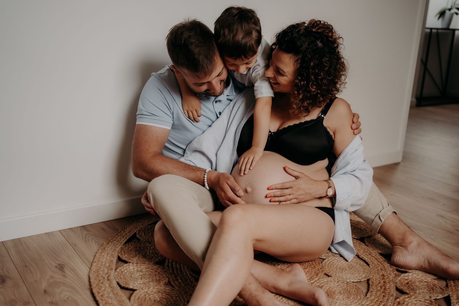 Couple shares tender moments on a round rug during an indoor maternity session.