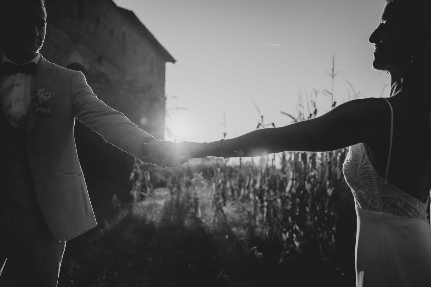 Silhouetted couple holding hands against dramatic sunset backlight creating magical atmosphere.