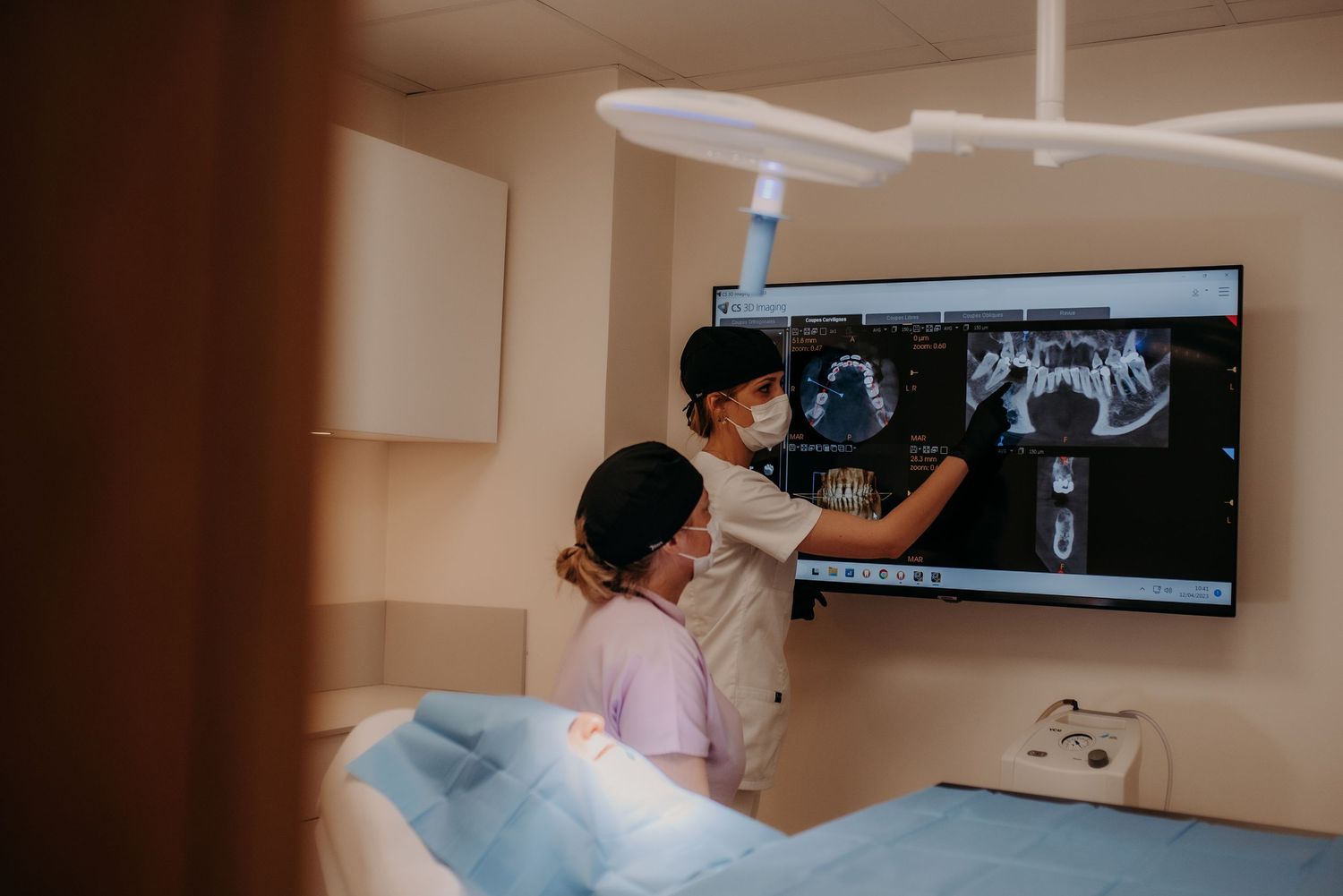 Medical professionals examining diagnostic images on wall-mounted screens in a clinical setting.
