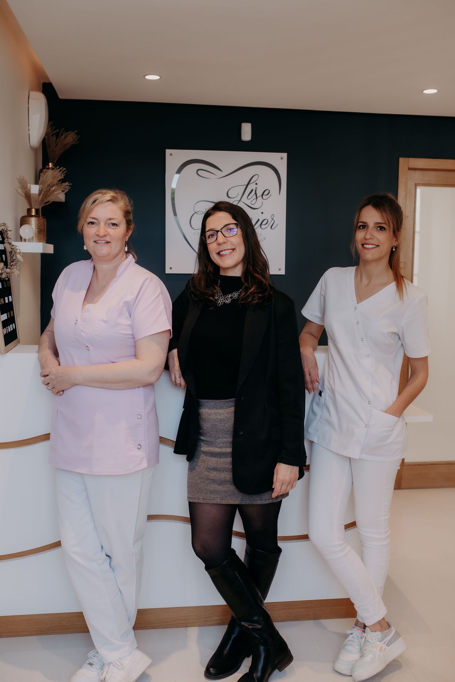 Healthcare workers in white uniforms posing together in a medical facility hallway.