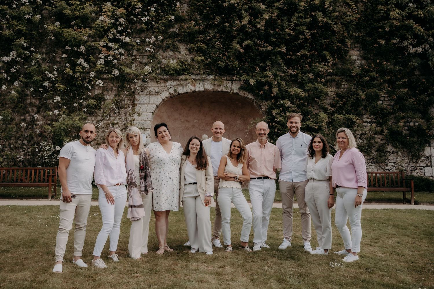 Large group photo of people dressed in white clothing posed outdoors on grass.