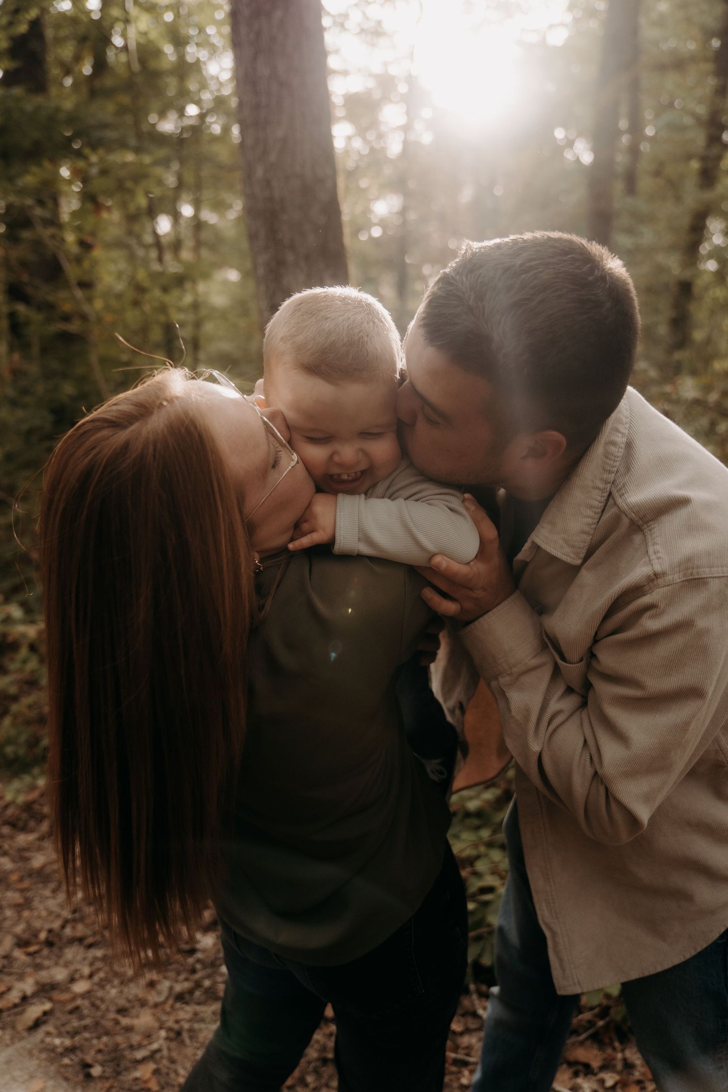Sweet family moment captured in sunlit wooded area during autumn.