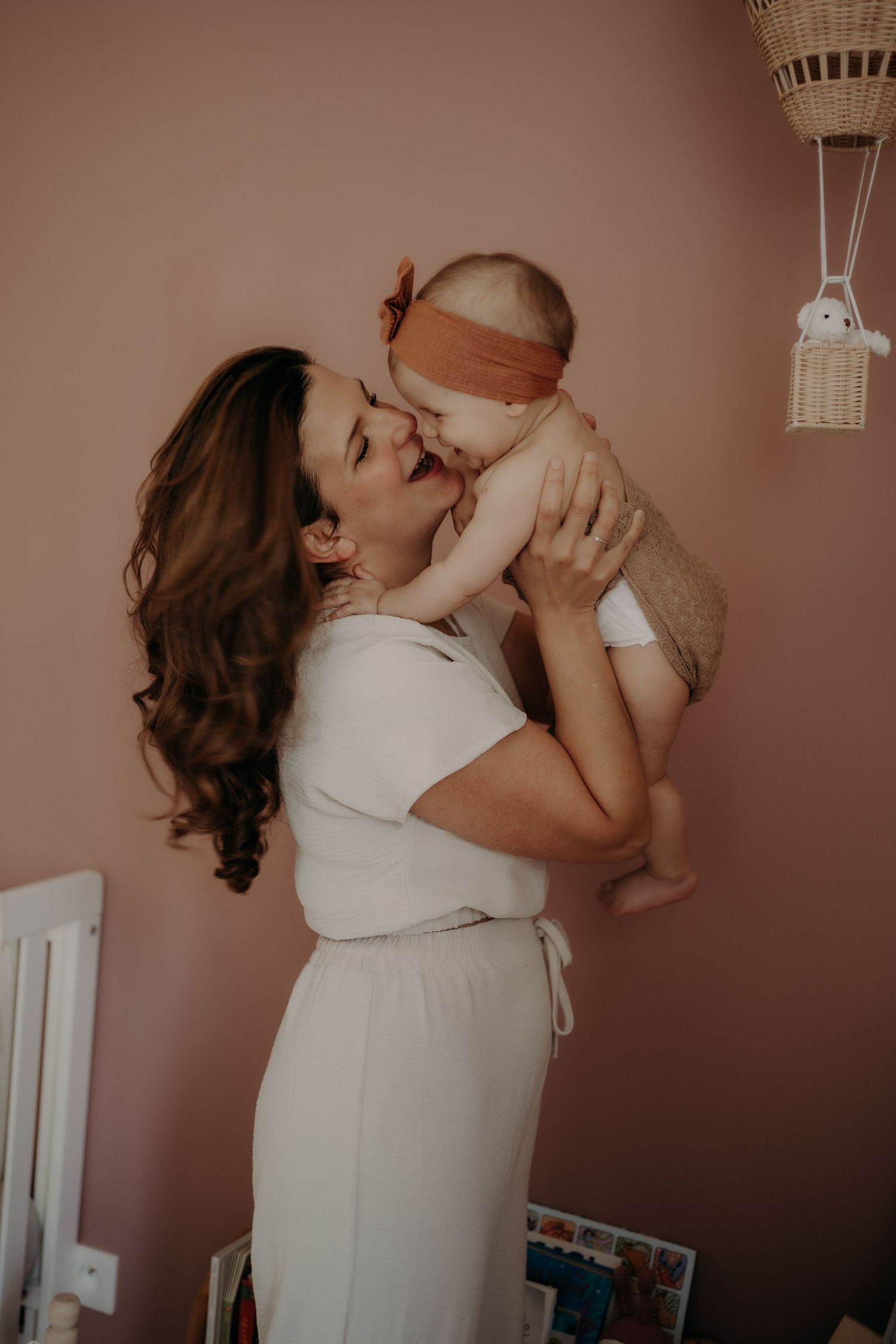 A tender moment captured in a nursery with soft pink walls and delicate lighting.