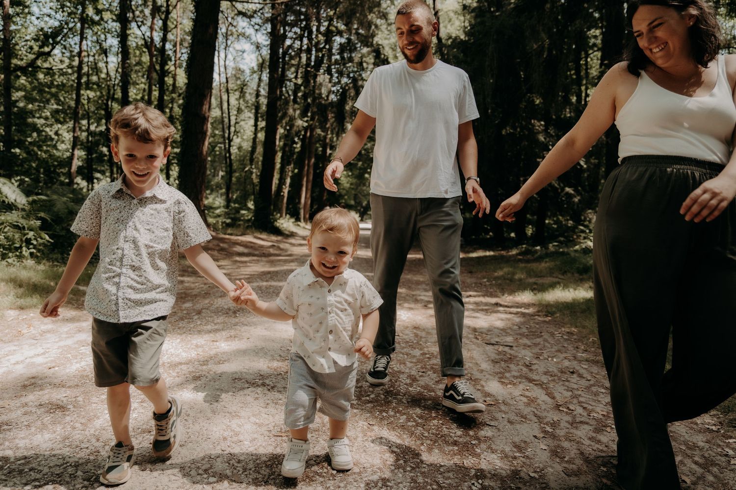 Family walking together on forest trail during summer day.