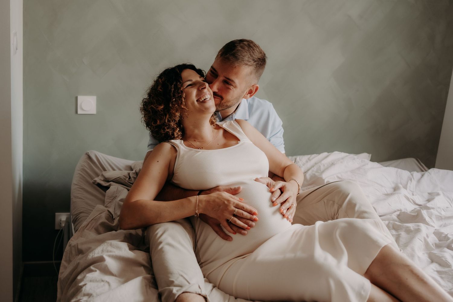 Intimate family moment captured on bed in soft, natural lighting.