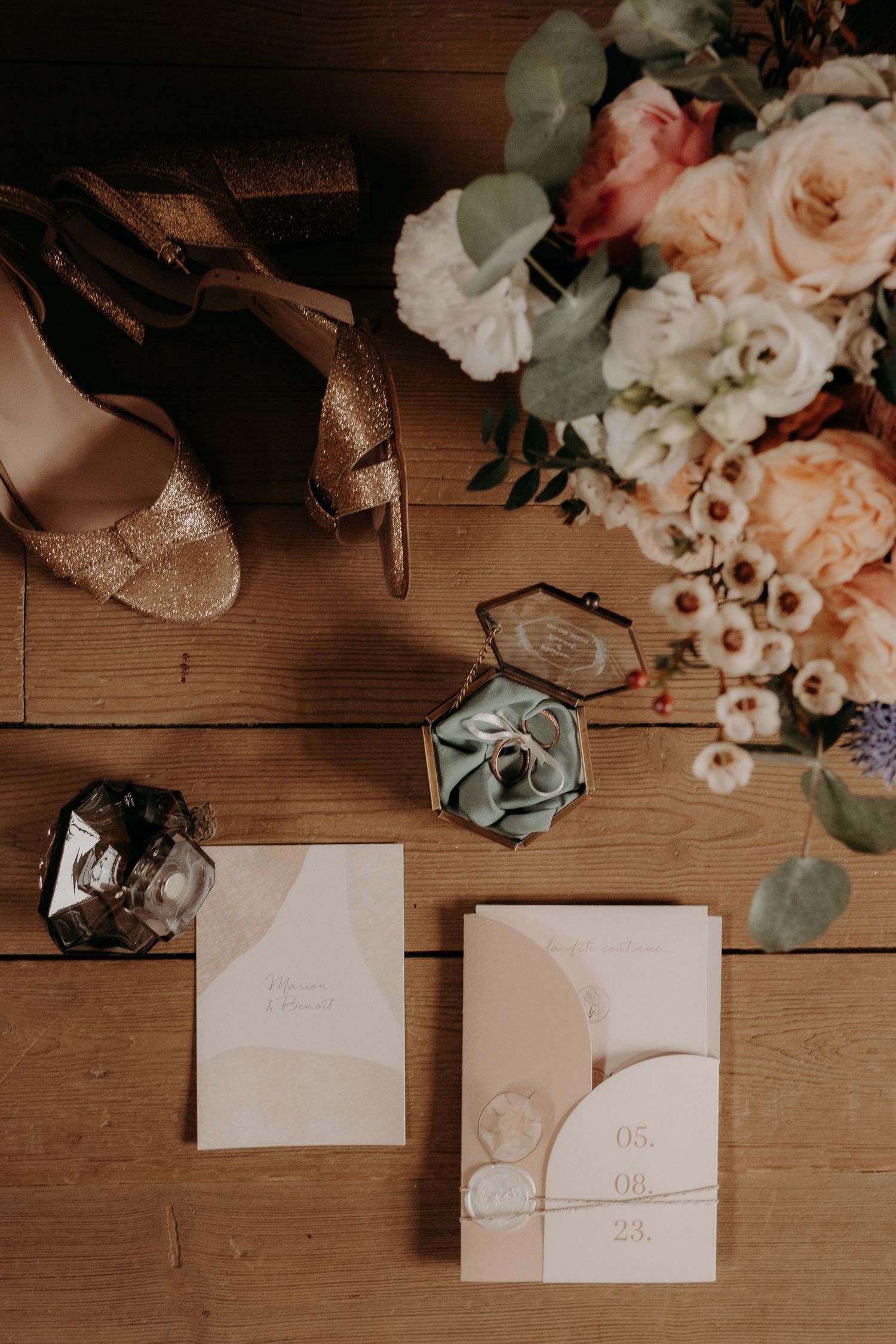 Wedding stationery and delicate flowers arranged on a rustic wooden surface with soft lighting.