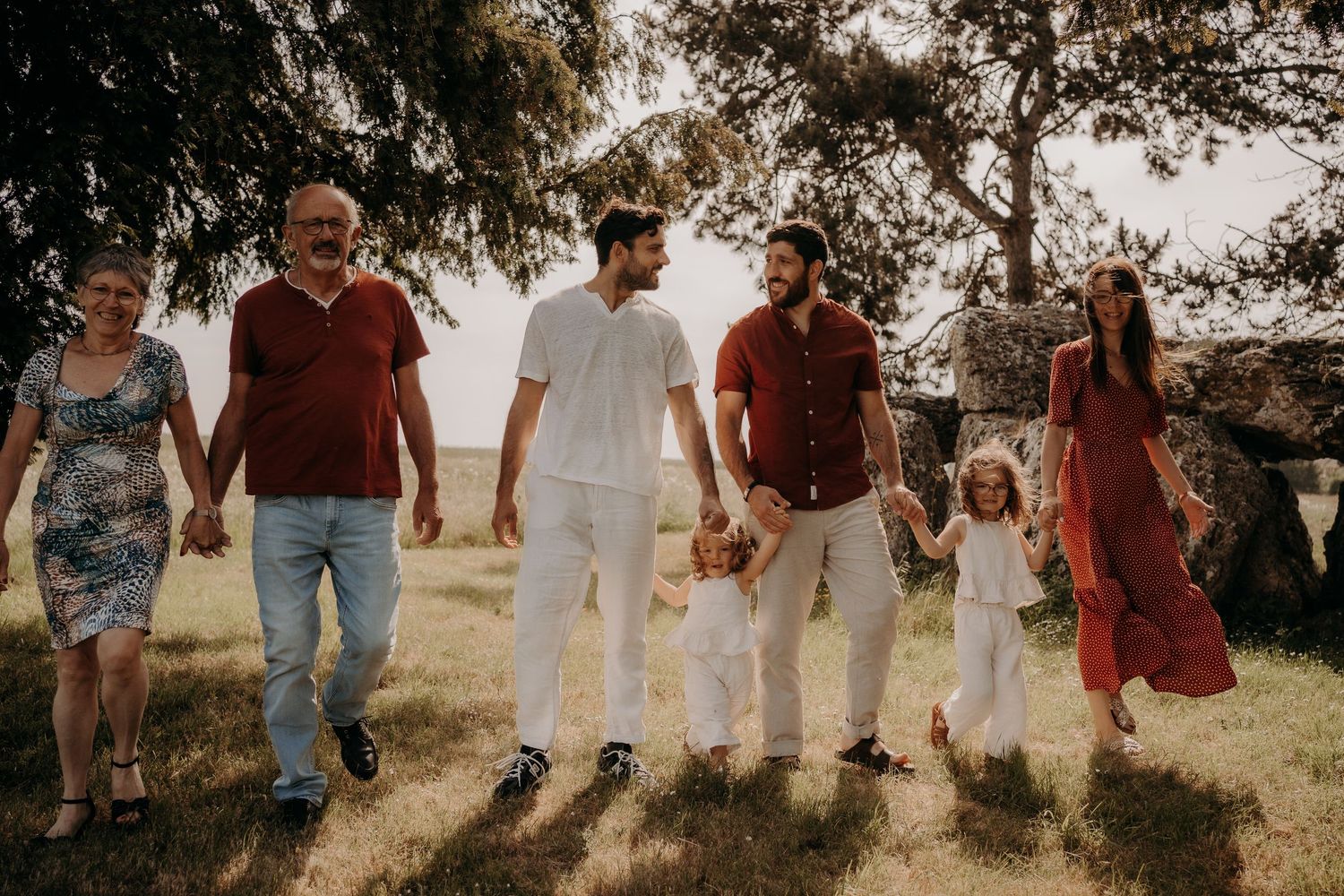 Group walking together across a grassy hillside during sunset in casual attire.