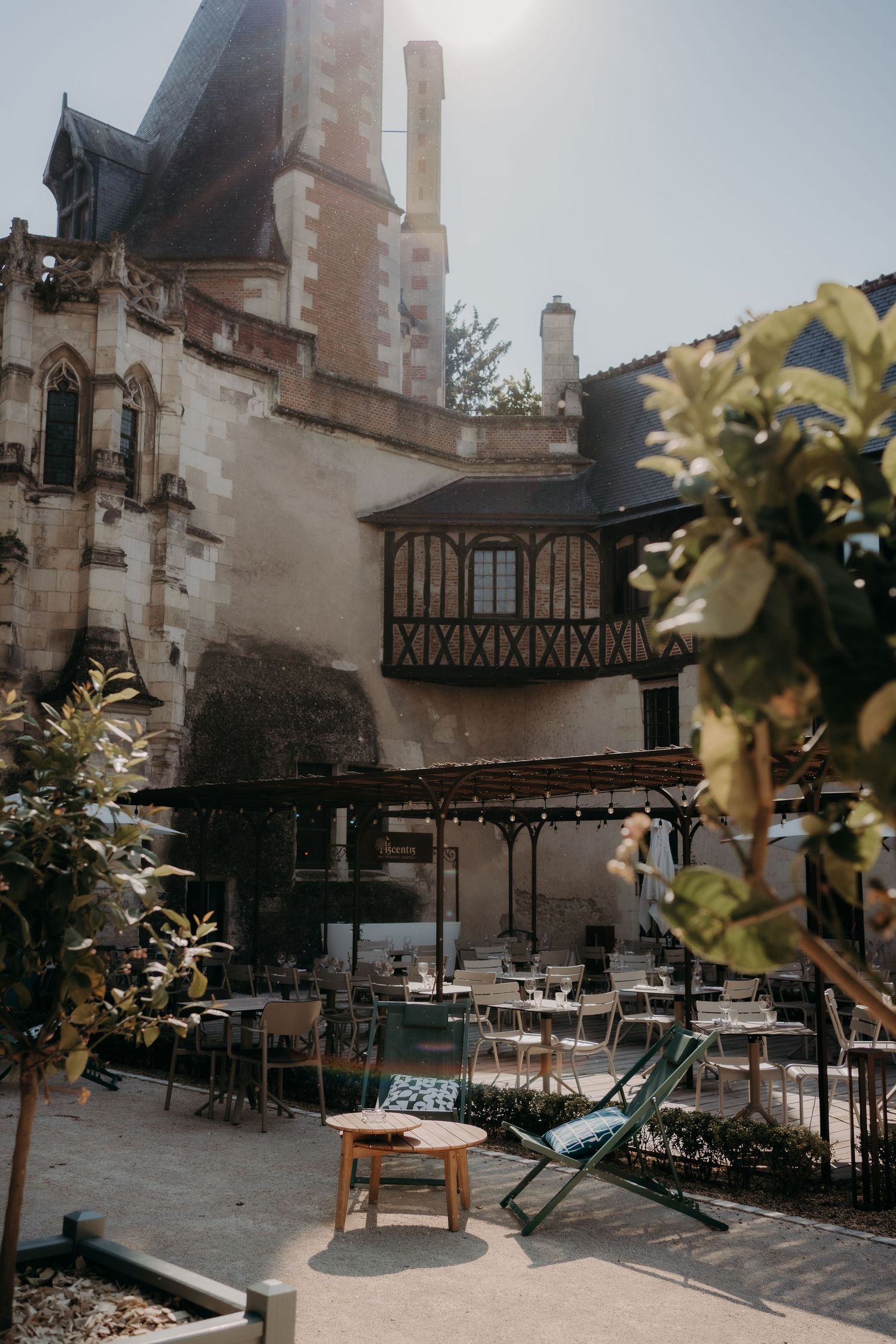 Outdoor restaurant terrace with tables set against historic stone building architecture.