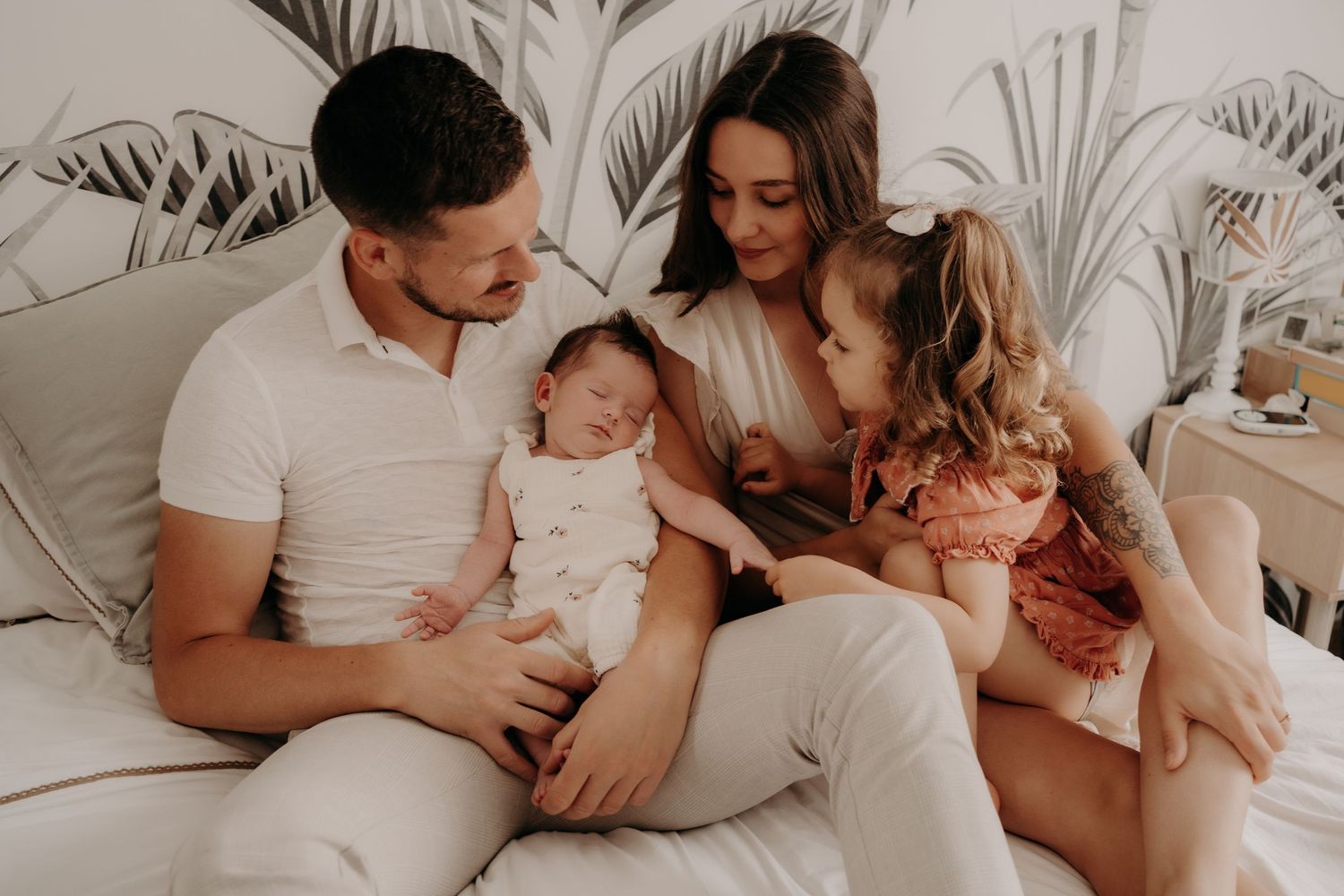 Intimate family portrait session on white bedding showing tender moments together.