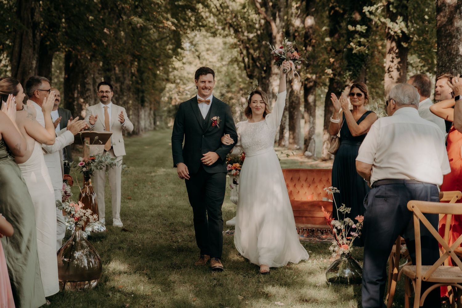 Outdoor wedding ceremony setup with guests seated in garden setting.