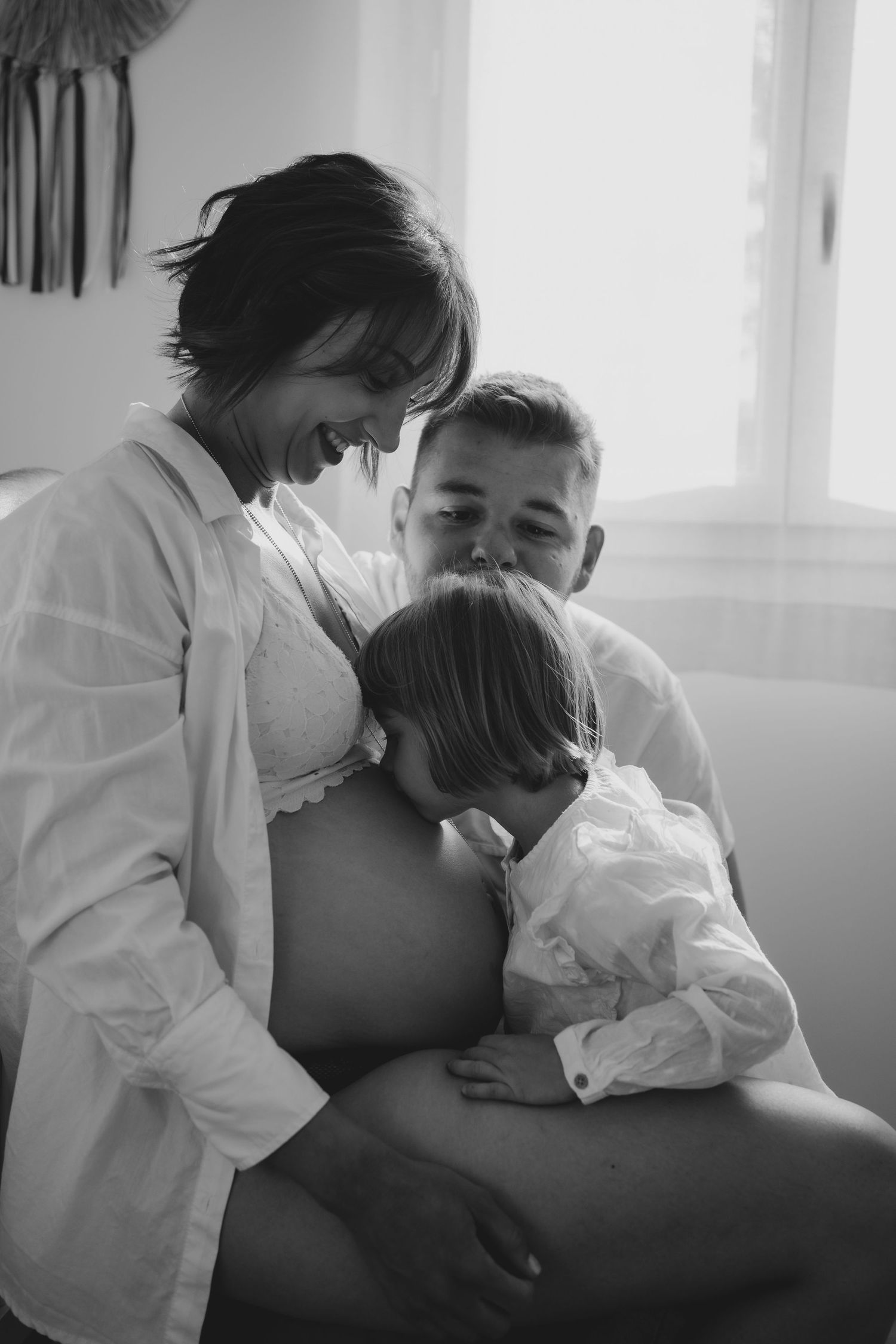 Intimate black and white maternity moment with family members.