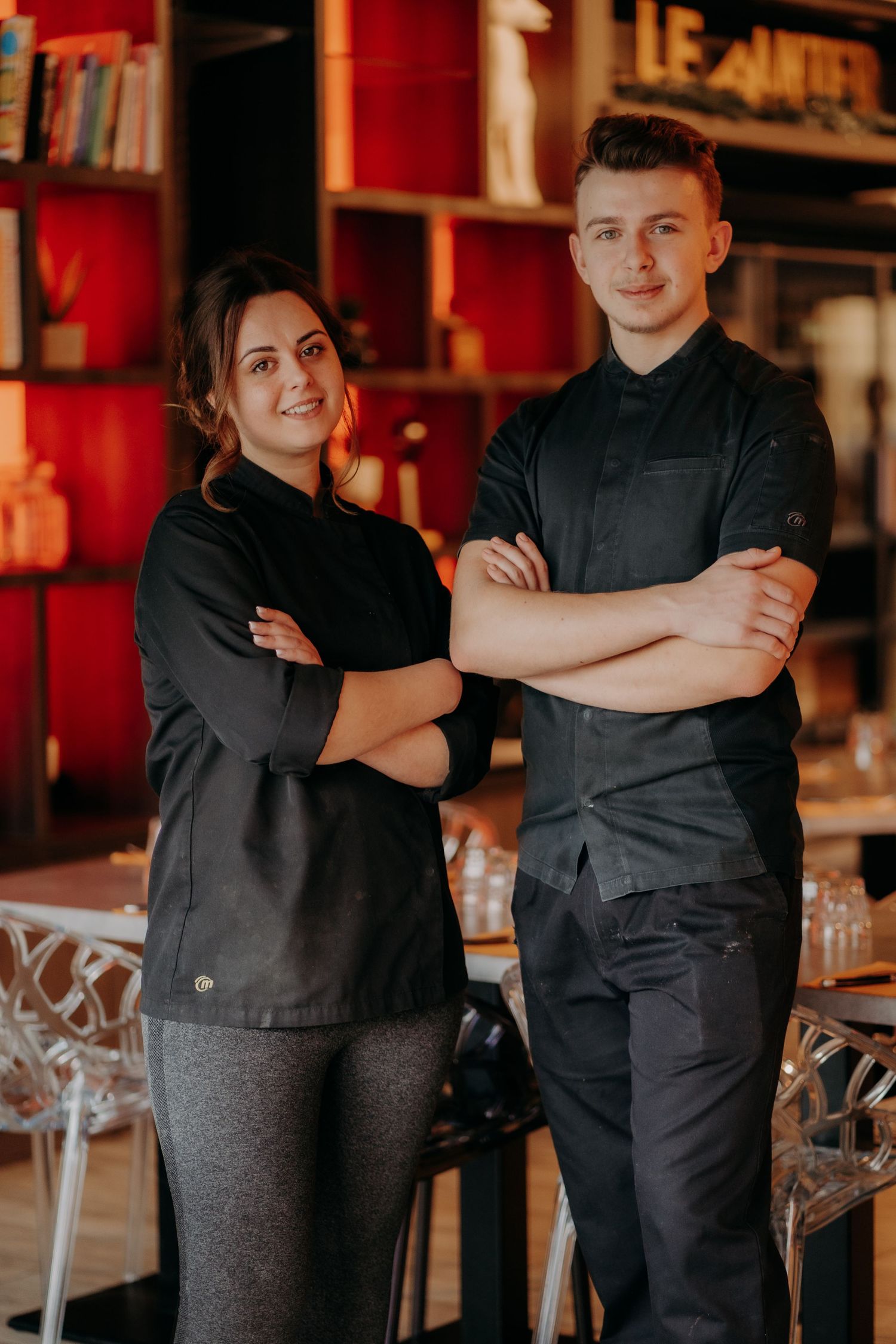 Restaurant staff in black uniforms posing together in a dining establishment.