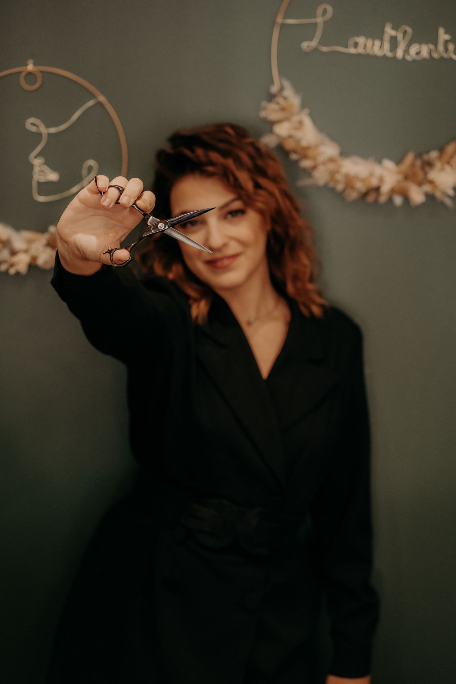 Woman with curly hair in black outfit making playful poses against dark background.