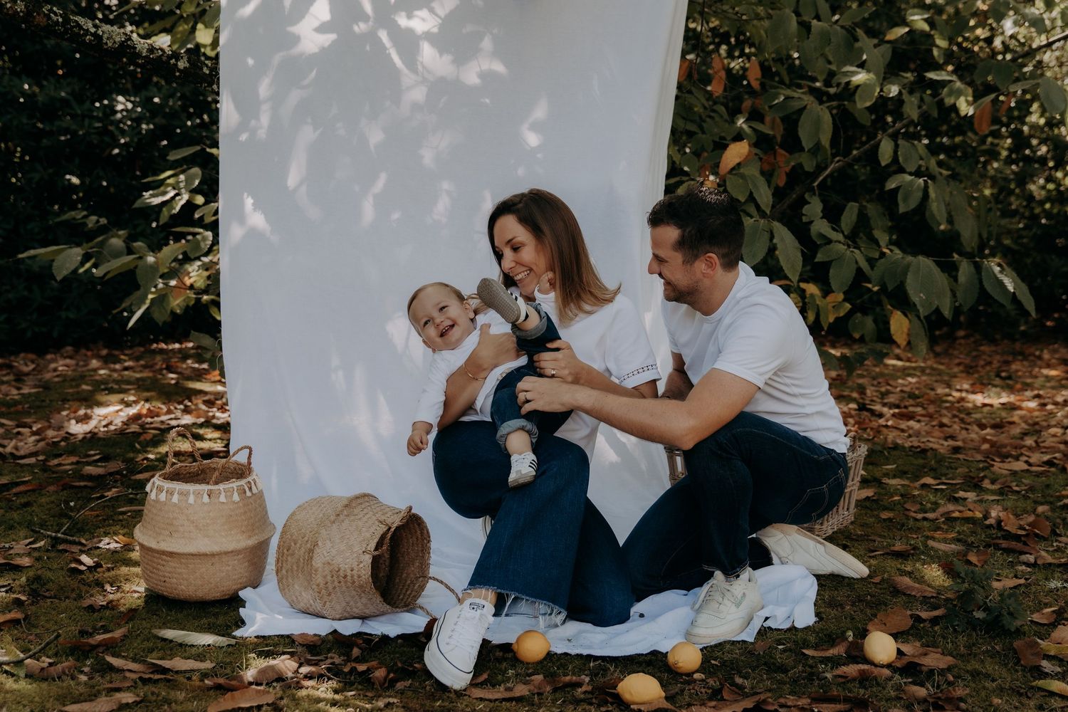 Intimate family photo session against white backdrop outdoors in natural setting.