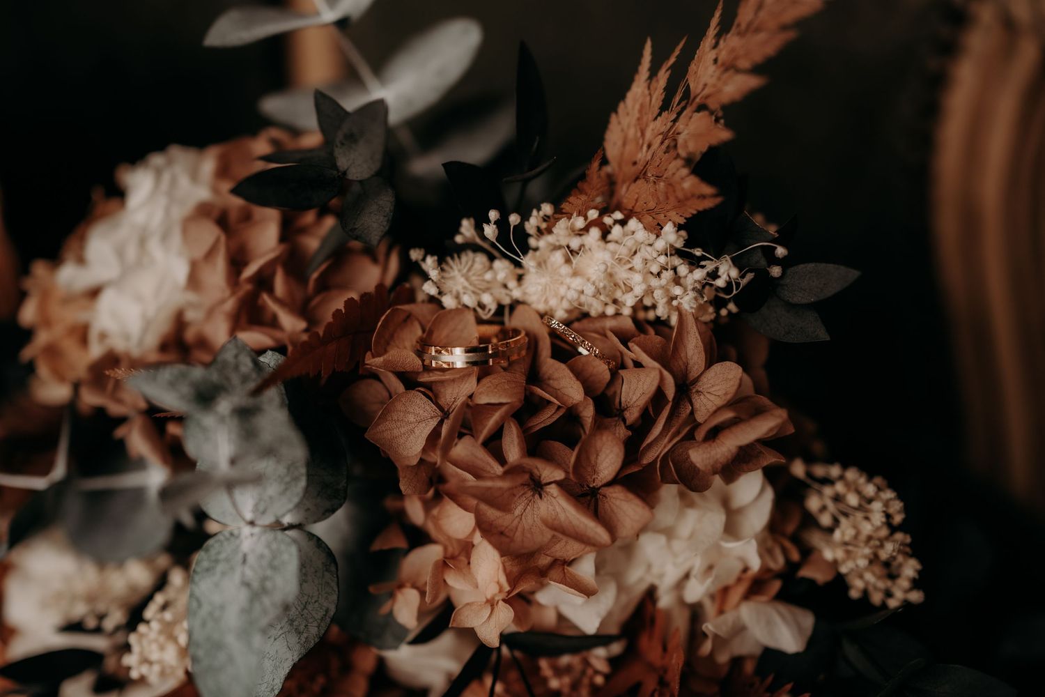 Artistic close-up of wedding floral arrangements in warm, moody lighting.