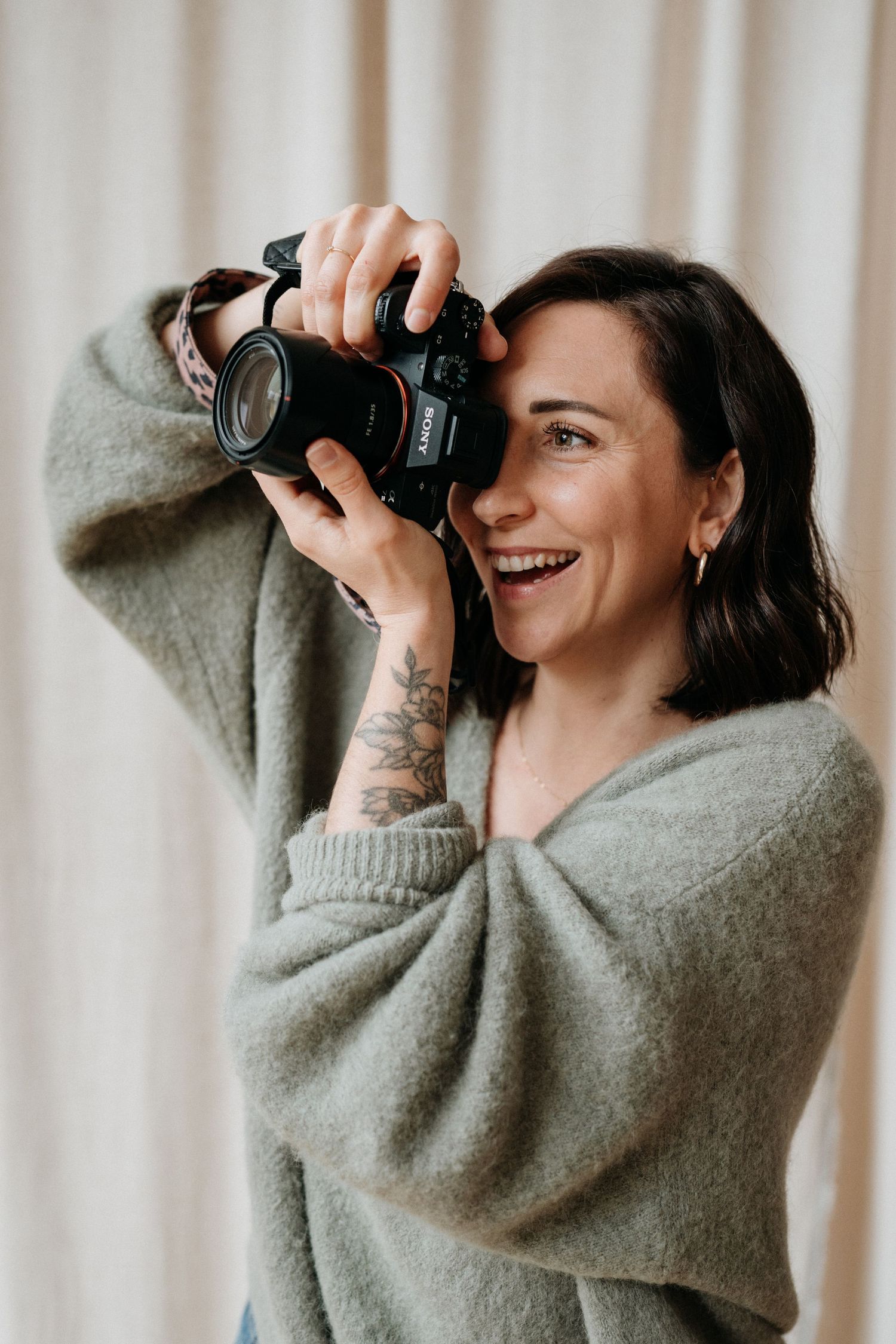 Photographer in cozy gray sweater taking pictures with a digital camera.
