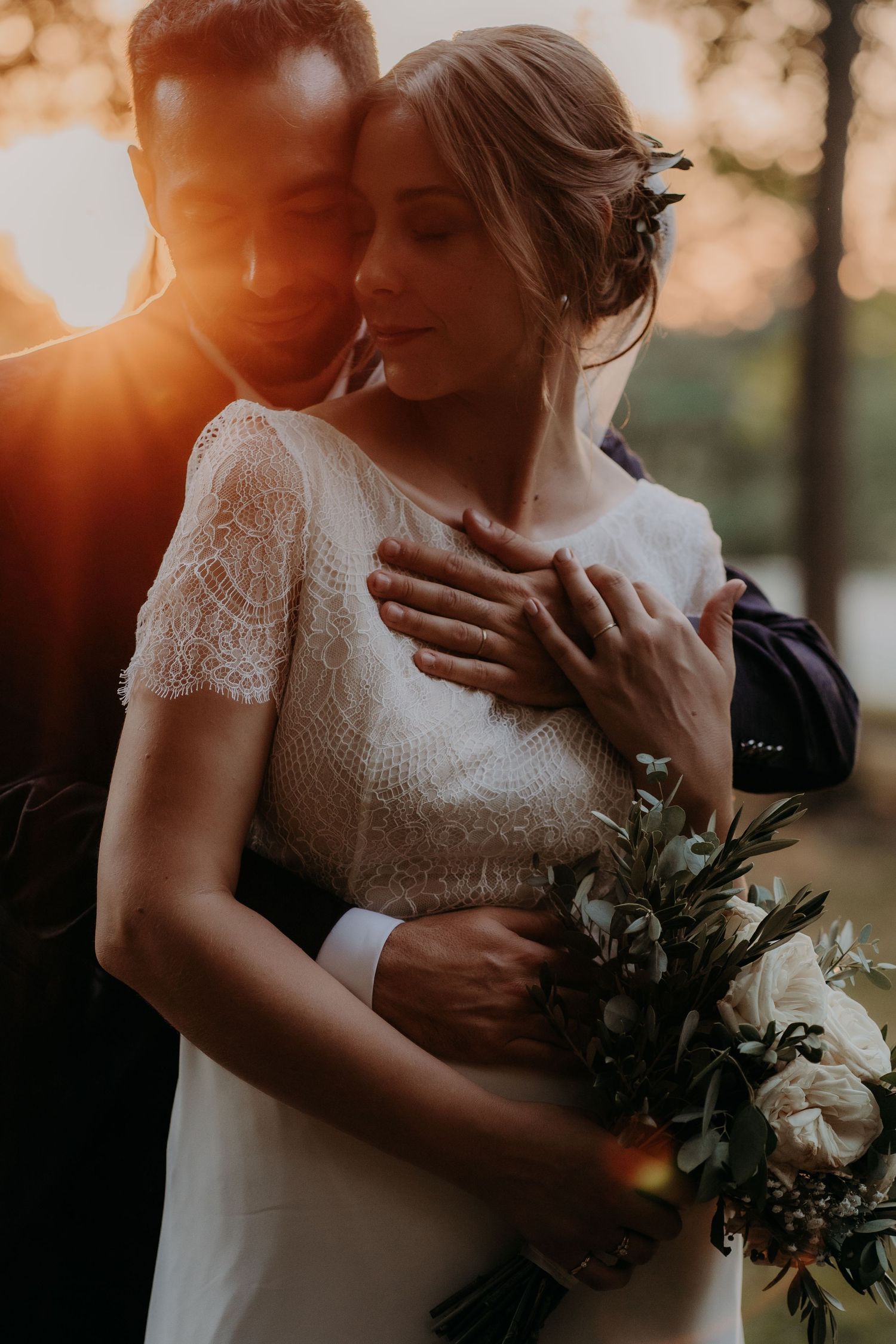 Romantic sunset wedding portrait with soft golden light filtering through trees.