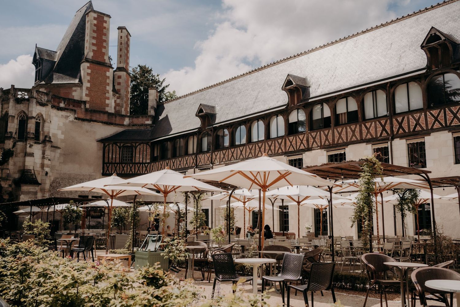 Tudor-style building exterior with outdoor seating area and umbrellas under cloudy sky.