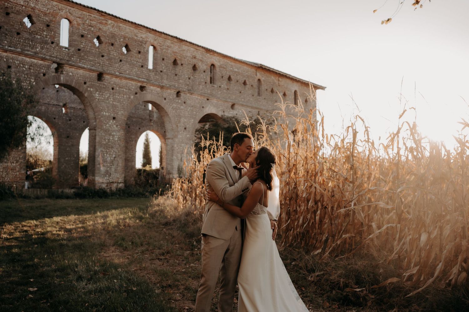 Romantic wedding photos captured against historic stone ruins at sunset.